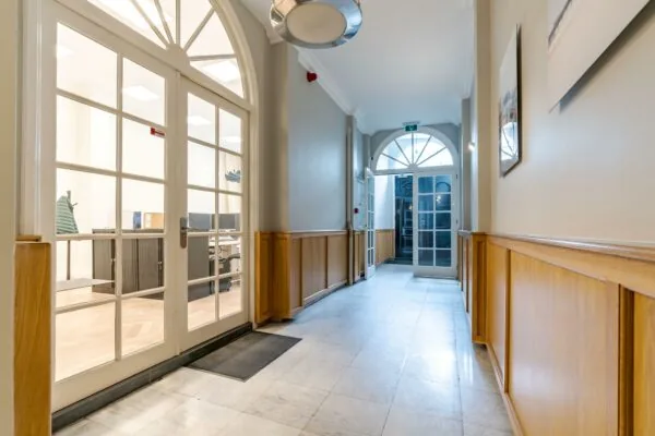 Lichte gang met houten lambrisering en glazen deuren in een kantoorpand aan de Lange Vijverberg.